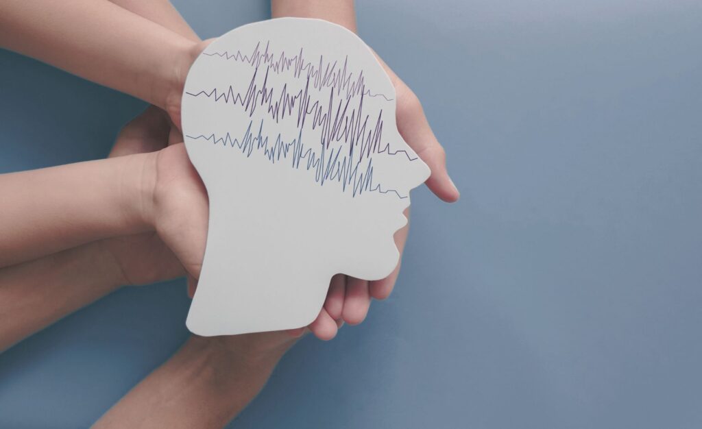 EEG (brain wave) studies in maryland as represented by an eeg cut out being carefully held in several hands